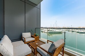 Un balcó amb vista al port esportiu, mobles de fusta i una planta en test.
