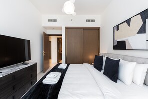 Et moderne hotelværelse med en stor seng, et fladskærms-tv, et klædeskab og et maleri på væggen.