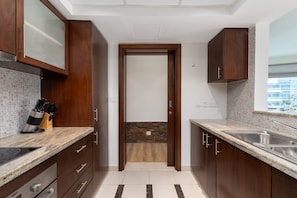 Una cocina moderna con armarios de madera, encimera de granito, horno empotrado y salpicadero de piedra.