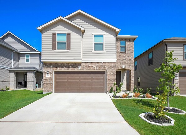 A two-story residential house with a garage, a front lawn, and a brick facade.