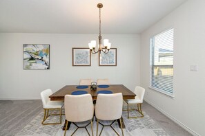 A dining room with a wooden table, six chairs, a chandelier, and artwork on the walls. - Spacious 3BR Home with Large Deck for family sleeps 6 (Converse)