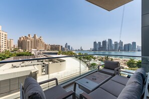 Un balcón con vista a la ciudad, que incluye edificios altos y una playa.