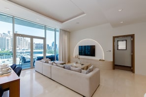 Una sala de estar moderna con un sofá grande, una mesa de comedor y un televisor montado en la pared.