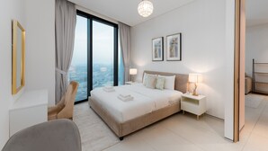 Ein modernes Hotelzimmer mit einem großen Bett, zwei Nachttischen, einem Sessel und Blick auf die Stadt, sowie einem großen Fenster.