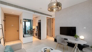 Ein modernes Wohnzimmer mit Fernseher, Essbereich und einer Küche im Hintergrund.