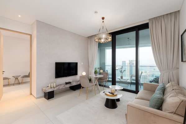Ein modernes Wohnzimmer mit Fernseher, Sofa, Couchtisch und einem Balkon mit Blick auf die Stadt.