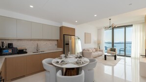 A modern kitchen with a dining area, a sofa, and a view of the sea. - Chic 2BR w/ Sea Views | Near Marina & JBR (Dubai)