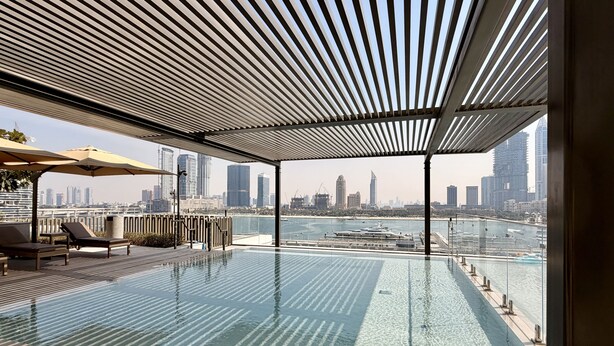 An infinity pool with a city skyline view, lounge chairs, and umbrellas. - Exquisite 2BR | Private Beach Access | Near Marina & JBR (Dubai)