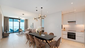 A modern kitchen with white cabinets, a built-in oven, and a dining area with a dark table and chairs. - Address JBR 2BR | Steps to Beach & Bluewaters (Dubai)