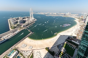 Vista aèria d'una ciutat costanera amb una platja extensa, un port esportiu i edificis moderns.