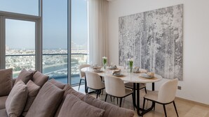 A modern dining area with a city view, a large abstract painting, and a comfortable seating arrangement. - Grand 3BR Beachfront Living | Palm Jumeirah (Dubai)