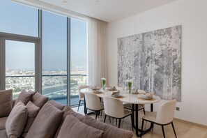 A modern dining area with a city view, a large abstract painting, and a comfortable seating arrangement. - Grand 3BR Beachfront Living | Palm Jumeirah (Dubai)