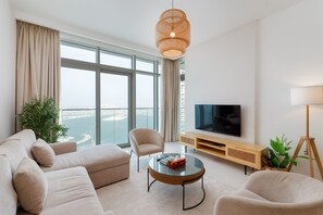 Ein modernes Wohnzimmer mit großem Fenster, einer Couch, einem Couchtisch, einem Fernseher und einer Lampe.