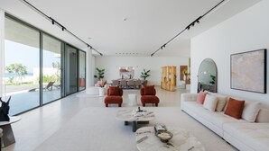 A spacious living area with a large window, a sofa, two armchairs, and a coffee table.