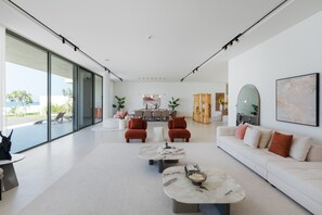 Amplia sala de estar con un ventanal grande, un sofá, dos sillones y una mesa de centro.