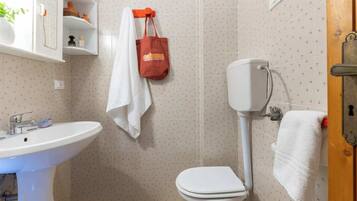Une salle de bain avec un lavabo blanc, des toilettes et une serviette accrochée au mur.