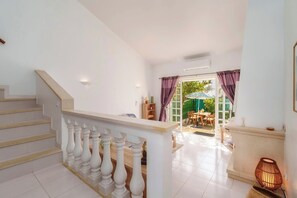 A staircase with white balusters, a wooden floor, and a view of an outdoor patio area with a table and chairs. - Cosy 2bedroom townhouse 10mns from Olhos de Agua (Albufeira)