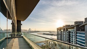 A modern building with a glass balcony overlooking a river and cityscape. - 4BR Palm Penthouse: Private Pool & Beach Access (Dubai)