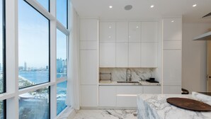 A modern kitchen with large windows, a marble countertop, and a city view. - 4BR Palm Penthouse: Private Pool & Beach Access (Dubai)