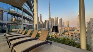 Eine Dachterrasse mit Liegestühlen und Blick auf die Skyline, einschließlich des Burj Khalifa.