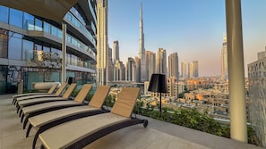 Eine Dachterrasse mit Liegestühlen und Blick auf die Skyline, einschließlich des Burj Khalifa.