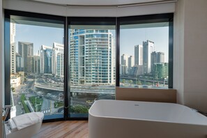Ein modernes Badezimmer mit einer großzügigen Badewanne, Blick auf eine Stadtkulisse durch raumhohe Fenster und einer Eckanordnung.