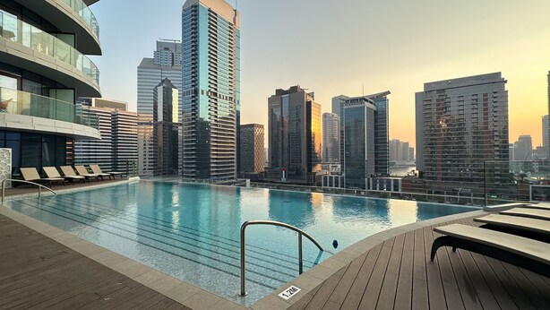 Una piscina sul tetto con lettini e uno skyline urbano sullo sfondo.