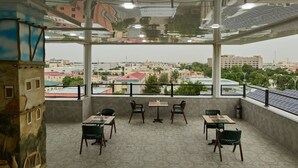 A rooftop terrace with tables and chairs, a city view, and solar panels. - Safia Plaza Hotel (Bukhara)