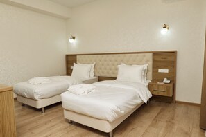 Habitació d'hotel amb dos llits, una taula de nit amb telèfon i una làmpada de paret.