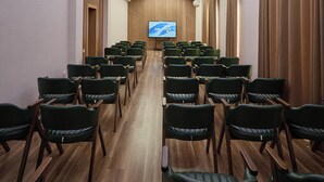 A conference room with rows of chairs, a large screen, and recessed ceiling lights. - Safia Plaza Hotel (Bukhara)