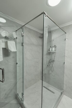 Een moderne badkamer met een douche met glazen wand, marmeren tegels en een handdoekhouder.