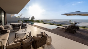 A modern outdoor patio with a pool, seating area, and a view of the ocean. - 4BR Coastal Haven w/  Private Pool | Al Zorah (Ajman)