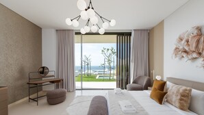 A modern bedroom with a large bed, a desk, and a view of the outdoors. - 4BR Coastal Haven w/  Private Pool | Al Zorah (Ajman)