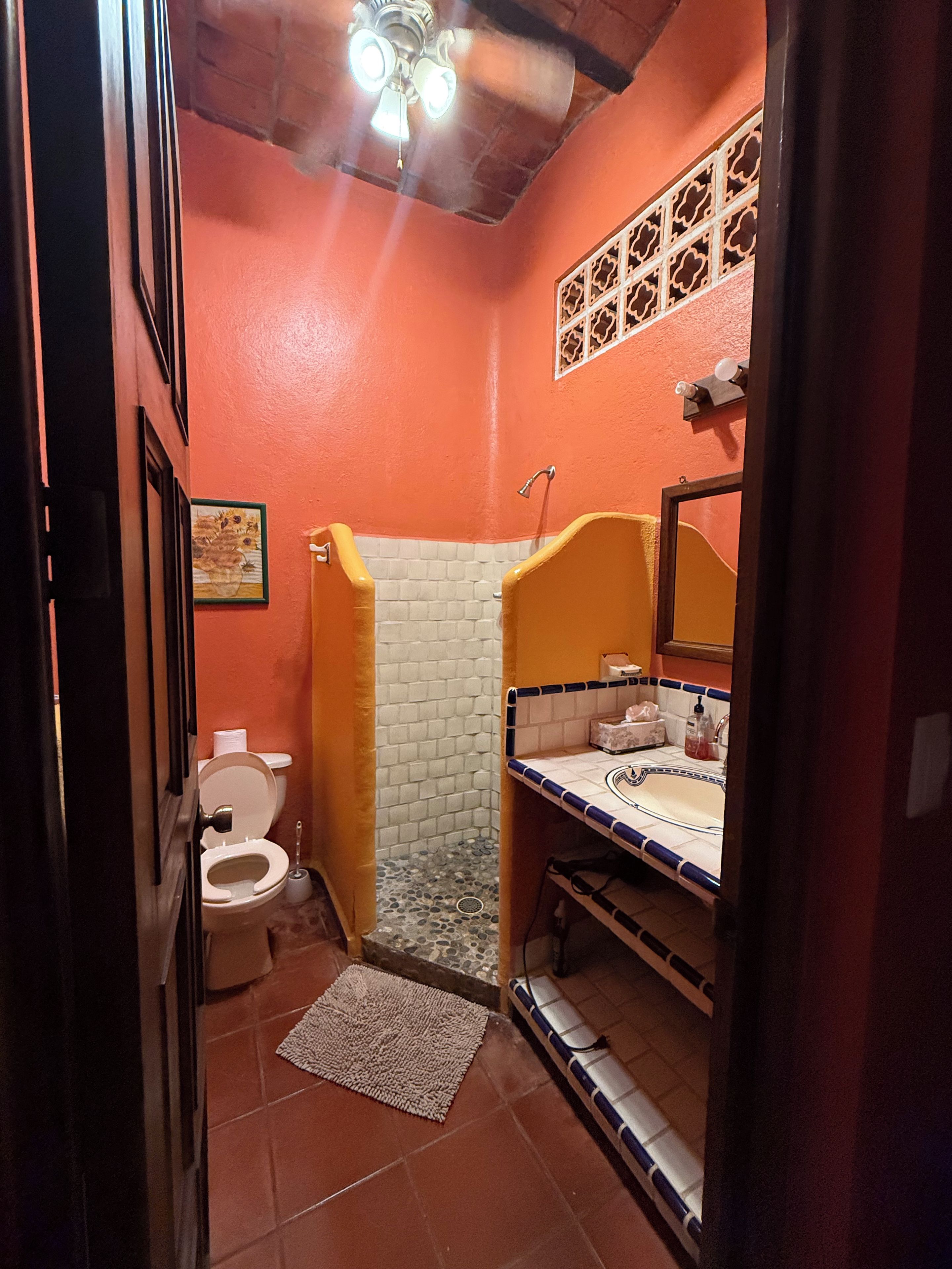 A compact bathroom with a toilet, shower, and sink.