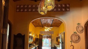 A hallway with a ceiling fan, a patterned wall, and a door leading to a kitchen area. - Casa Sorpresa mexican charm by the beach (Sayulita)