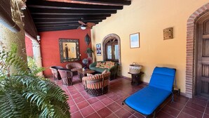 A covered outdoor seating area with a lounge chair, wicker chairs, and a table. - Casa Sorpresa mexican charm by the beach (Sayulita)