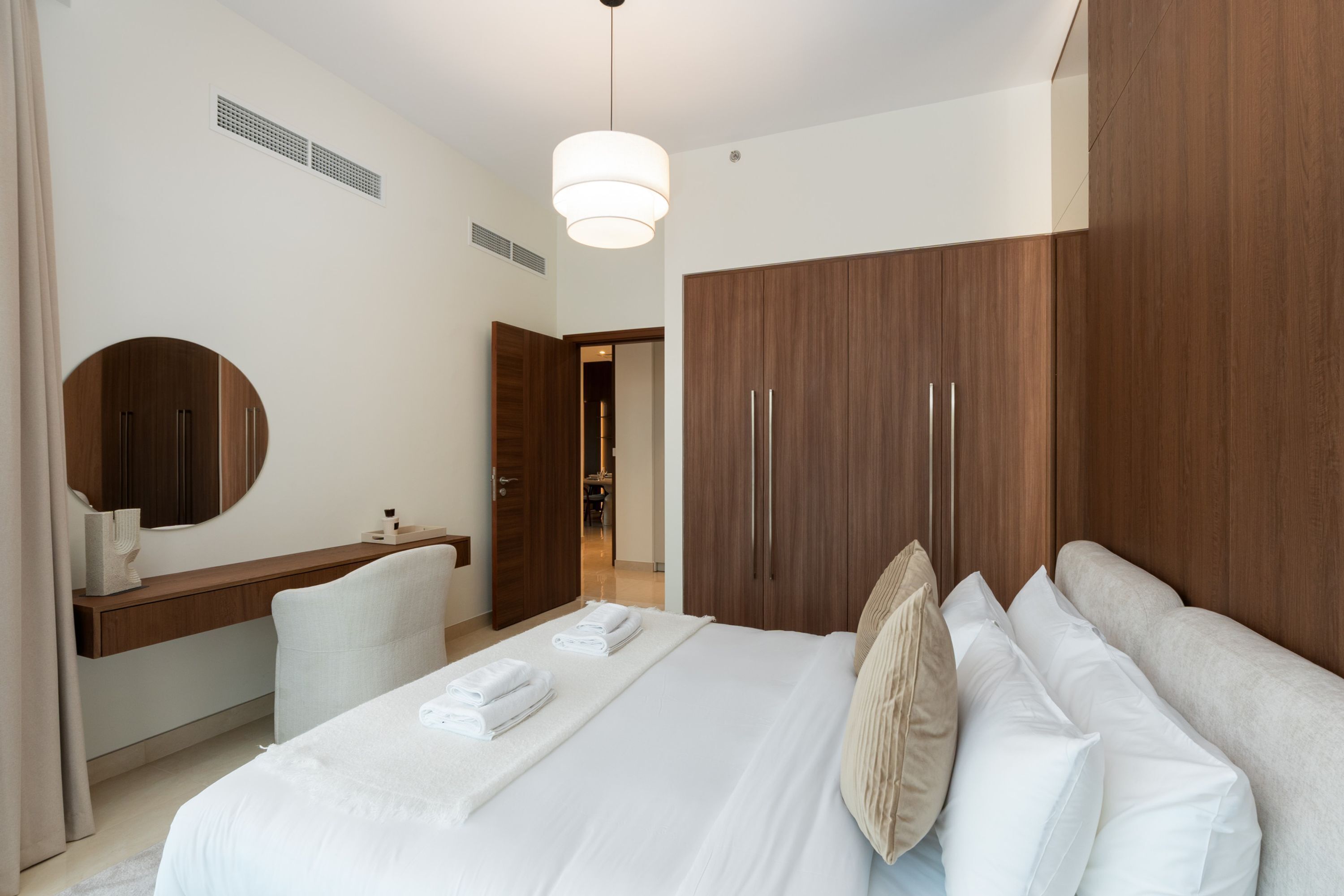 Une chambre d’hôtel avec un lit, un bureau, un miroir et une armoire.