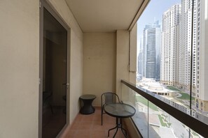 Ein Balkon mit Tisch und Stühlen, Blick auf hohe Gebäude und ein gefliester Boden.