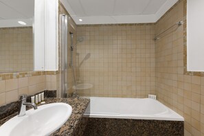 Ein Badezimmer mit Waschbecken, Spiegel, Dusche und Fliesenwänden.