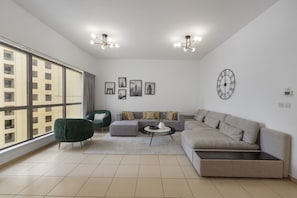 Ein modernes Wohnzimmer mit großem Fenster, einer Couch, einem Couchtisch und einem grünen Sessel.