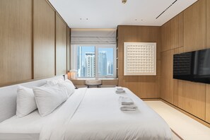 Una habitación de hotel moderna con una cama grande, televisor de pantalla plana y vistas a la ciudad.