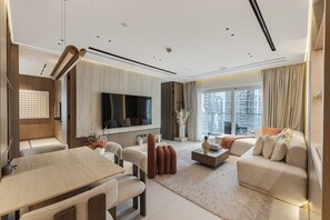 Una sala de estar moderna con televisión de pantalla plana, comedor y un conjunto de sofás.