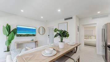 A modern kitchen with a built-in refrigerator, a dining area with a wooden table, and a view of the ocean.