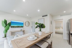 A modern kitchen with a built-in refrigerator, a dining area with a wooden table, and a view of the ocean. - The Palmetto: Boca Pool Suite + Beach (Boca Raton)