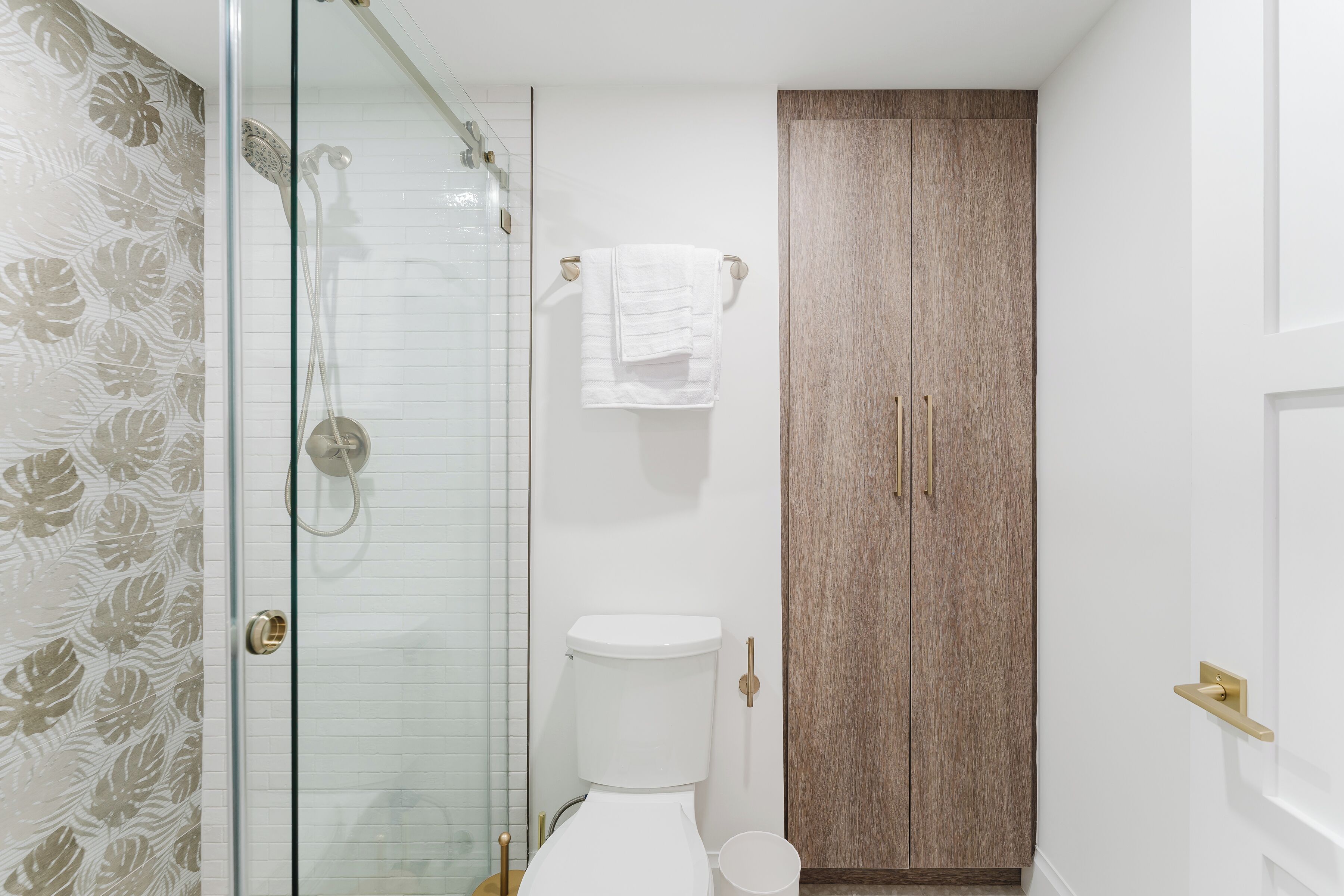 Ein Badezimmer mit Duschkabine aus Glas, Toilette und Holztür.