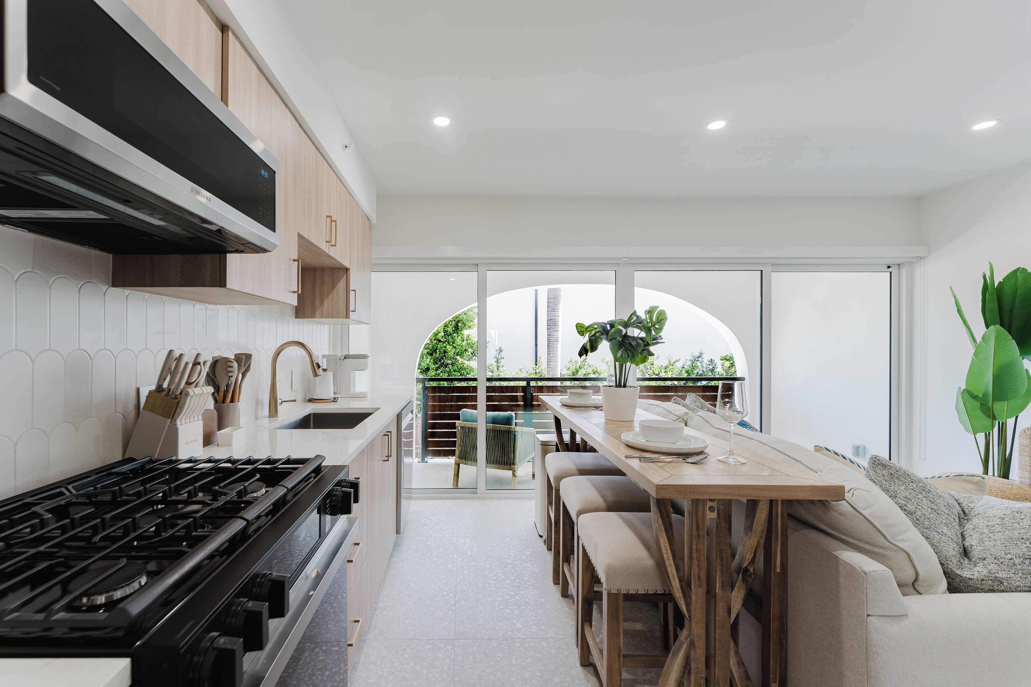 A modern kitchen with a gas stove, wooden cabinets, and a dining area with a table and chairs.