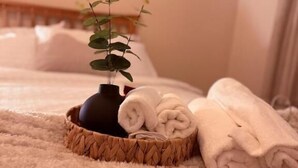 Ein Bett mit gerolltem Handtuch und einer kleinen Topfpflanze auf einer flauschigen Decke.