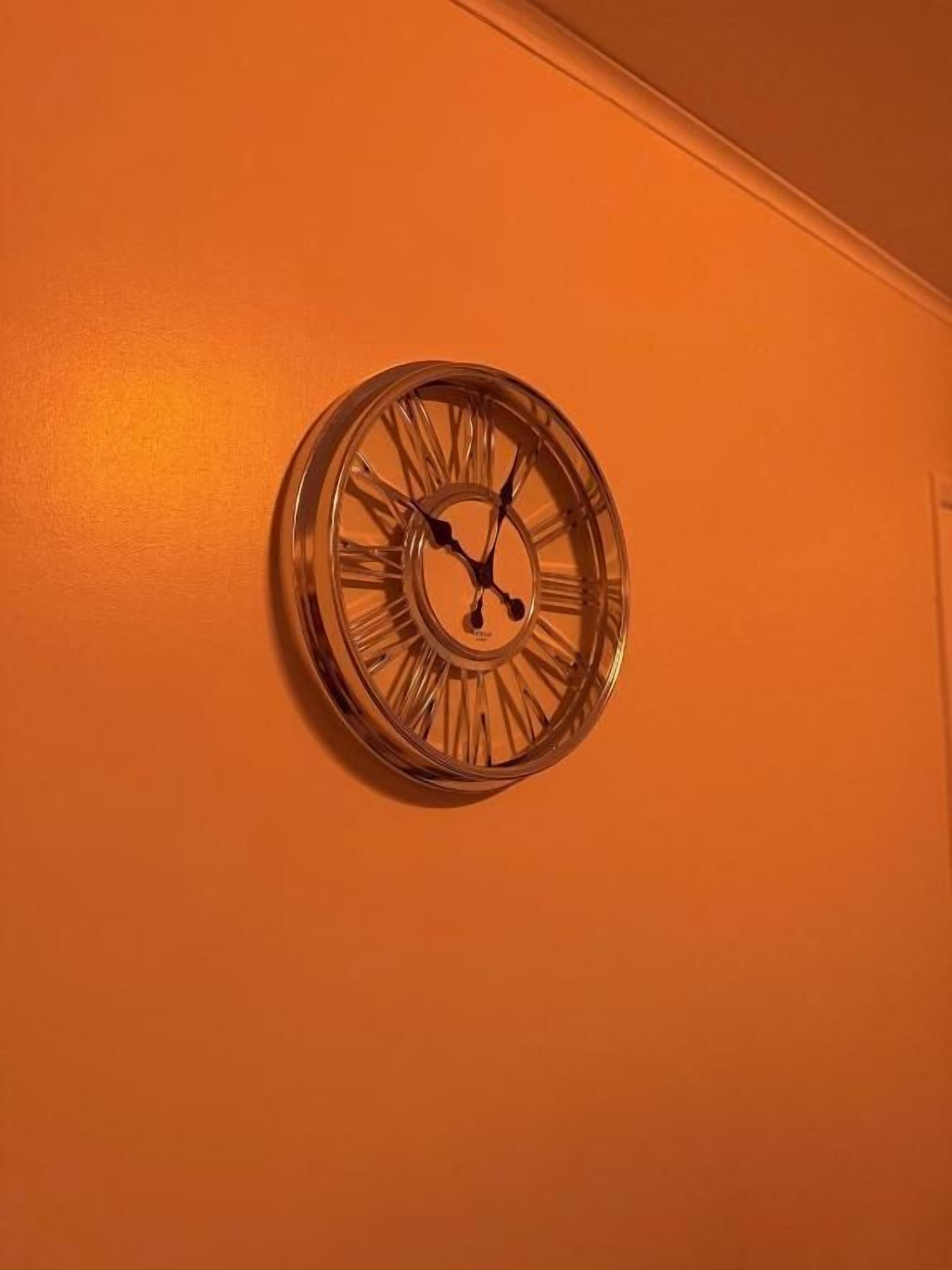 A wall-mounted clock with Roman numerals.