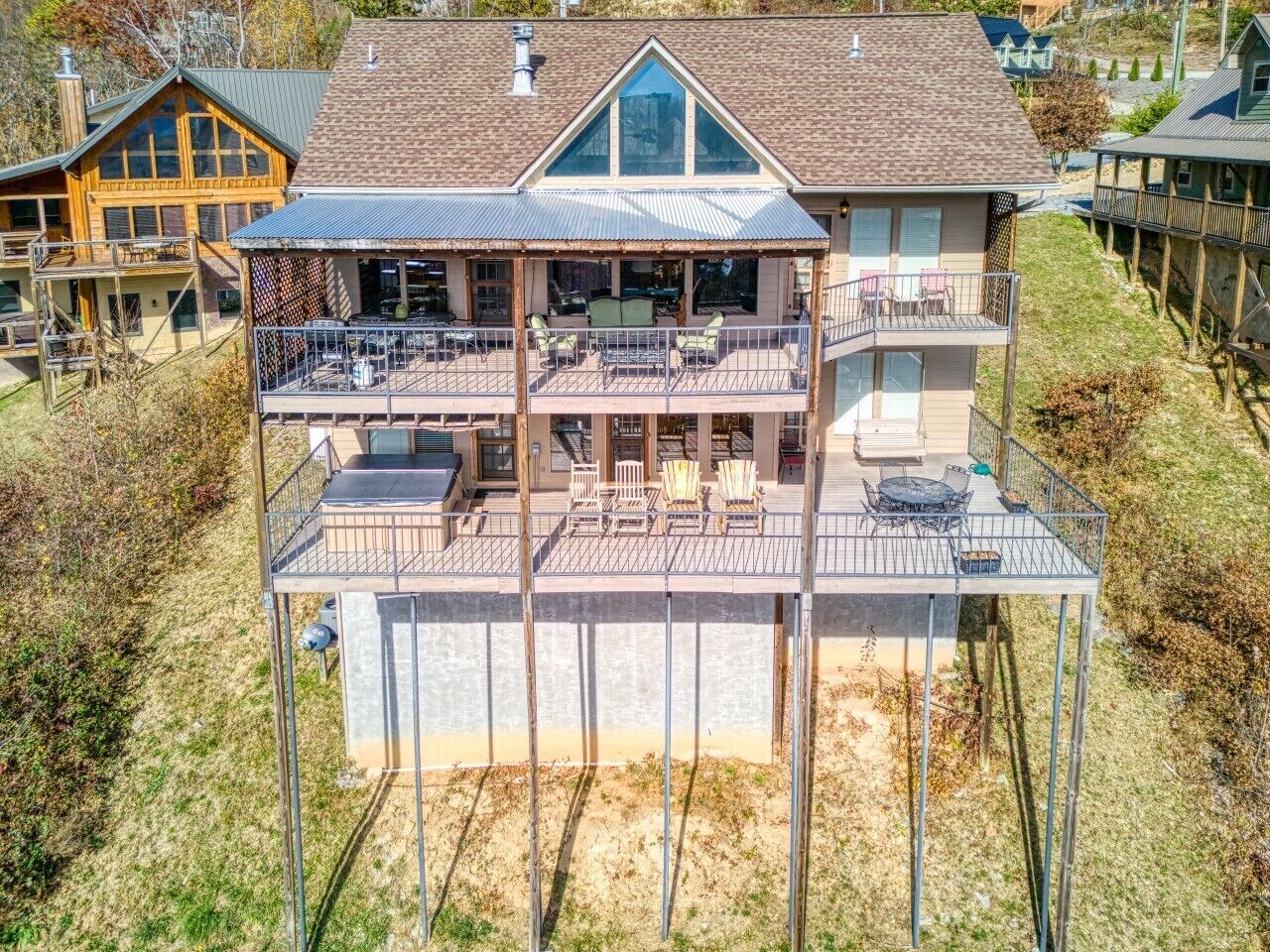 A two-story house with a balcony, outdoor seating area, and a large window.