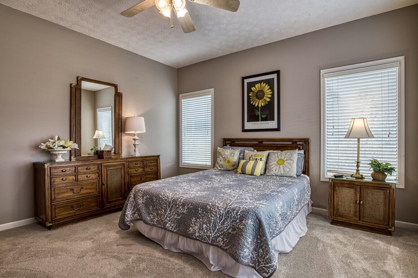 A bedroom with a bed, dresser, mirror, and two bedside lamps.